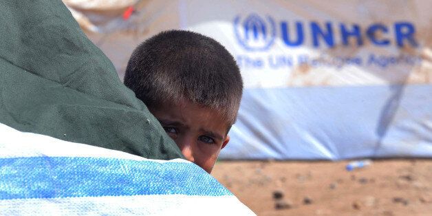 A Syrian refugee boy peeps behind a tent at the Quru Gusik refugee camp on the outskirts of Arbil in Iraq's Kurdistan region, August 23, 2013. The number of Syrian children forced to flee their devastated homeland reached 1 million on Friday, half of all the refugees driven abroad by a conflict that shows no sign of ending, the United Nations said. Another two million Syrian minors are uprooted within their country where they are often attacked, recruited as fighters, and deprived of their education, the U.N. refugee agency UNHCR and U.N. Children's Fund (UNICEF) said. REUTERS/Stringer (IRAQ - Tags: CIVIL UNREST POLITICS SOCIETY)