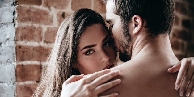 Close-up of beautiful young shirtless couple hugging while woman looking over shoulder of her boyfriend