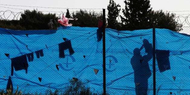 A migrant hangs clothes to dry behind a wire fence of a refugee camp in the western Athens' suburb of Schisto, Monday April 4, 2016, during the first day of the implementation of the deal between EU and Turkey. Under the deal, migrants arriving illegally in Greece will be returned to Turkey if they do not apply for asylum or if they make an asylum claim that is rejected. (AP Photo/Lefteris Pitarakis)
