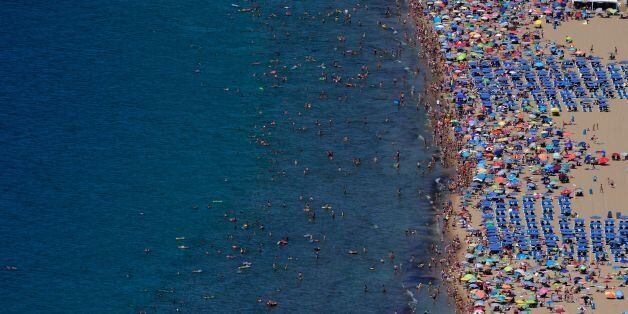 Beach goers swim and sun bath in Benidorm, near Alicante on August 9, 2016. / AFP / JOSE JORDAN (Photo credit should read JOSE JORDAN/AFP/Getty Images)
