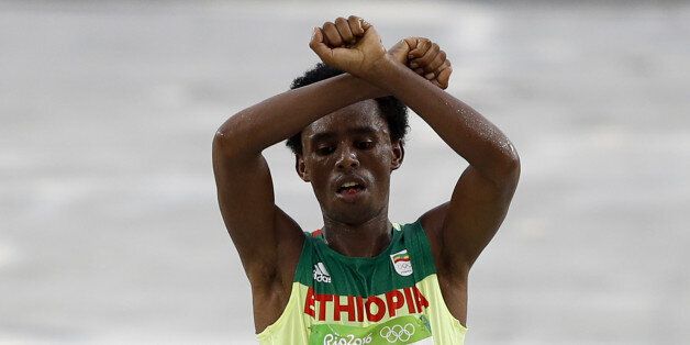 TOPSHOT - Ethiopia's Feyisa Lilesa (silver) crosses the finish line of the Men's Marathon athletics event during the Rio 2016 Olympic Games at the Sambodromo in Rio de Janeiro on August 21, 2016. Lilesa crossed his arms above his head as he finished the race as a protest against the Ethiopian government's crackdown on political dissent. / AFP / Adrian DENNIS (Photo credit should read ADRIAN DENNIS/AFP/Getty Images)