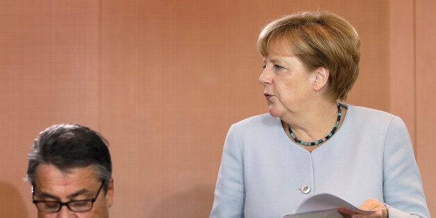 German Chancellor Angela Merkel, right, holds files as she arrives for the weekly cabinet meeting at the Chancellery in Berlin, Germany, Wednesday, Aug. 31, 2016. At left is Vice-Chancellor, Sigmar Gabriel. (AP Photo/Michael Sohn)