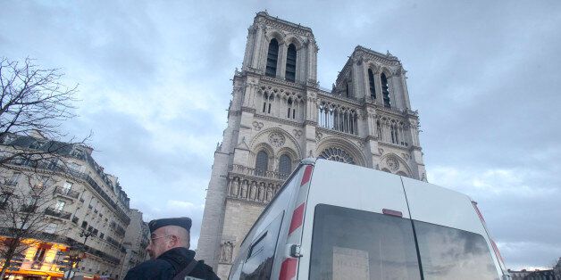 A French Police stand in front of Notre Dame cathedral, in Paris, Thursday, Dec. 25, 2015. France's interior minister Bernard Cazeneuve announced Tuesday that churches will keep only one door open, instead of multiple doors,