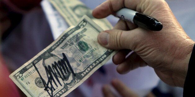 U.S. Republican presidential candidate Donald Trump hands a five-dollar bill back to a supporter after signing it for her following a rally with sportsmen in Walterboro, South Carolina February 17, 2016. REUTERS/Jonathan Ernst