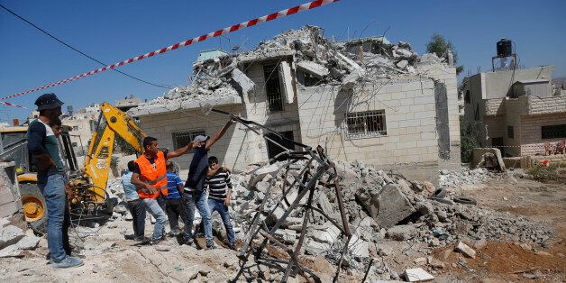Palestinians clean the debris at the family house of Khaled Mahamra after it was demolished by Israeli troops in the West Bank village of Yatta, south of Hebron, Thursday, August 4, 2016. Khaled and his cousin Mohammed Mahamra opened fire at a restaurant in Tel Aviv in June, killing four people in one of the deadliest attacks in a 10-month wave of Israeli-Palestinian violence. (AP Photo/Nasser Shiyoukhi)