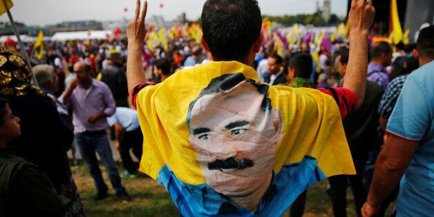 A protester flashes victory signs as he wears a flag with the image of Abdullah Ocalan, jailed leader of Kurdistan's Workers' Party PPK, during a rally of several thousands Kurdish Turks against Turkish President Recep Tayyip Erdogan and his leading AKP party in Cologne, Germany September 3, 2016. REUTERS/Wolfgang Rattay