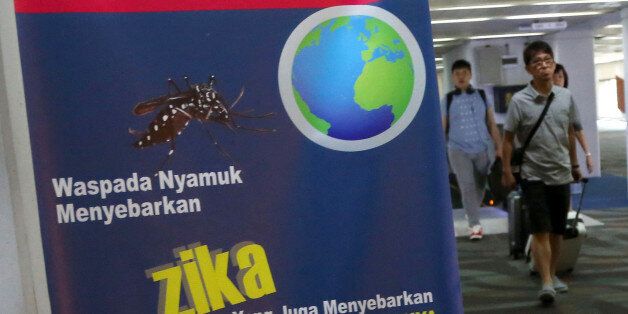 Arriving travelers walk past an nformation banner on Zika virus at Soekarno-Hatta International Airport in Tangerang, Indonesia, Friday, Sept. 2, 2016. Indonesia is screening travelers from Singapore for the mosquito-borne Zika virus as the city-state reports a growing number of infections. (AP Photo/Tatan Syuflana)