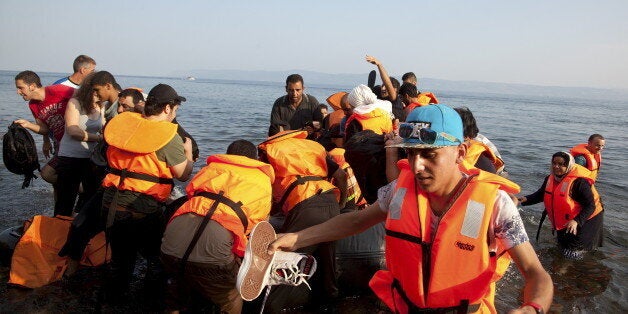 A Frontex helicopter patrols over Syrian refugees arriving on an overcrowded dinghy at a beach at the Greek island of Lesbos August 10, 2015. Thousands of refugees and migrants are stranded on Greek islands -- in some cases for over two weeks -- waiting for temporary documents before continuing their travel to northern Europe. The United Nations refugee agency (UNHCR) called on Greece to take control of the