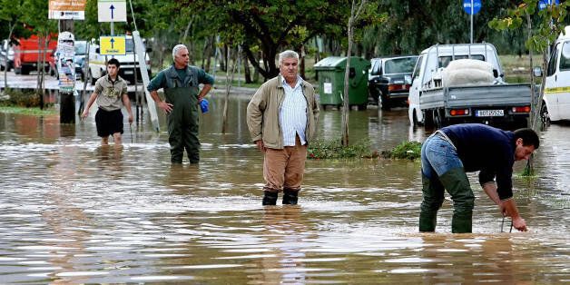 Volos, GREECE: Residents stand at a flooded street in the city of Volos, some 300 kilometres north of Athens, after an overnight heavy storm, 10 October 2006. Greece has experienced stormy weather since the weekend, with two regions now placed in a state of emergency because of flood-related problems that damaged homes and disrupted transport. AFP PHOTO / Paris Papaioannou (Photo credit should read PARIS PAPAIOANNOU/AFP/Getty Images)