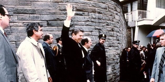 This photo taken by presidential photographer Mike Evens on March 30, 1981 shows President Ronald Reagan waving to the crowd just before the assassination attempt on him, after a conference outside the Hilton Hotel in Washington, D.C.. Reagan was hit by one of six shots fired by John Hinckley, who also seriously injured press secretary James Brady (just behind the car). Reagan was hit in the chest and was hospitalized for 12 days. Hinckley was aquitted 21 June 1982 after a jury found him mentally unstable. (Photo credit should read MIKE EVENS/AFP/Getty Images)