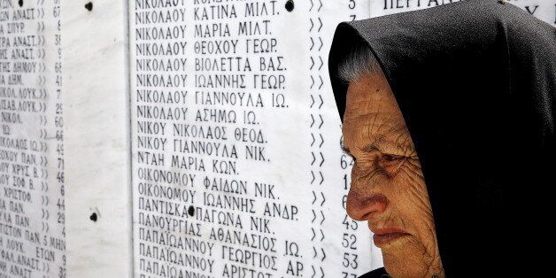 Survivor Loukia Gavrili, 86, sits by a plaque featuring the names of those killed by Nazi troops, on the day of the 71st anniversary of the Nazi wartime Distomo massacre, in the village of Distomo, in central Greece, June 10, 2015. On June 10, 1944, during the German occupation of Greece in World War Two, Waffen-SS troops of the 4th SS Polizei Panzergrenadier Division under the command of Fritz Lautenbach, burned the village of Distomo to the ground and killed 218 civilians, including women and children, in retaliation for an attack by partisans. Athens's demands for 278.7 billion Euros in reparations from Germany have gained momentum in recent years as Greeks suffer hardship during the economic crisis but while Berlin has repeatedly rejected the claims, some, including German President Joachim Gauck, have expressed their support Gavrili lost her sister and mother in the massacre. REUTERS/Yannis Behrakis TPX IMAGES OF THE DAY