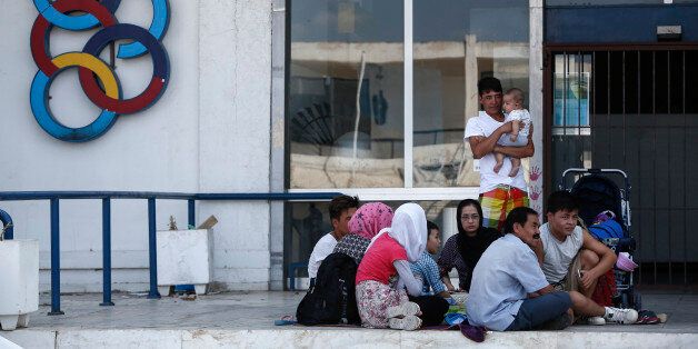 Migrants sit next to the Olympic Airlines logo at the premises of the old Athens' International airport in Athens, on Friday, Sept. 2, 2016. Some 60,000 migrants remain stranded on Greece's mainland and the islands since European border closures earlier this year. Under the EU-Turkey deal, migrants who arrived in Greece after March 20 can be deported back to Turkey. But most of the detention camps there are over capacity. (AP Photo/Yorgos Karahalis)