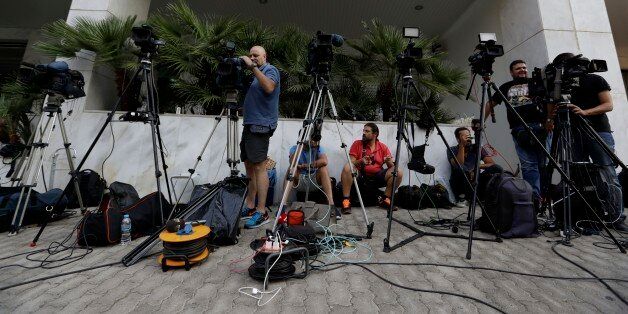 TV crews work outside the Greek Secretariat General for Media and Communication in Athens on Wednesday, Aug. 31, 2016 where eight bidders are taking part for second day in the process that would see eliminated TV stations close by the end of the year. Greece's left-wing government launched an auction Tuesday for four private national television licenses, reducing the number from seven after a heated public debate on corruption in the financially troubled country. (AP Photo/Thanassis Stavrakis)