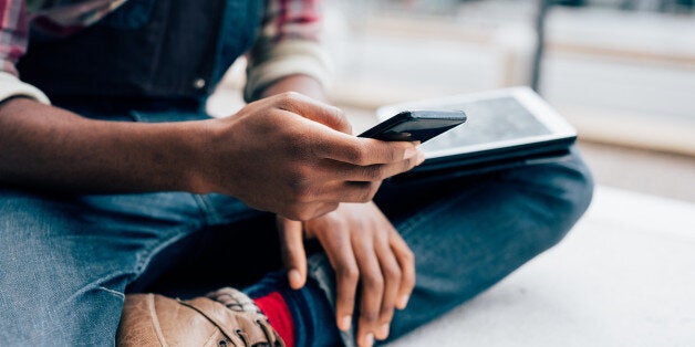 Close up on the hands of a young handsome afro black man using a smartphone, tapping the screen - technology, social network, communication concept