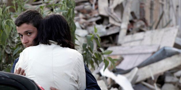 Two people hug each other next to the remains of a collapsed house following an earthquake in Pescara Del Tronto, Italy, Wednesday, Aug. 24, 2016. The magnitude 6 quake struck at 3:36 a.m. (0136 GMT) and was felt across a broad swath of central Italy, including Rome where residents of the capital felt a long swaying followed by aftershocks. (AP Photo/Gregorio Borgia)