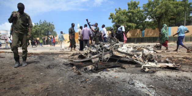 A Somali policeman walks past the wreckage of a car destroyed during an explosion outside the headquarters of Somalia's Criminal Investigation Department (CID) in the capital Mogadishu, July 31, 2016. REUTERS/Ismail Taxta