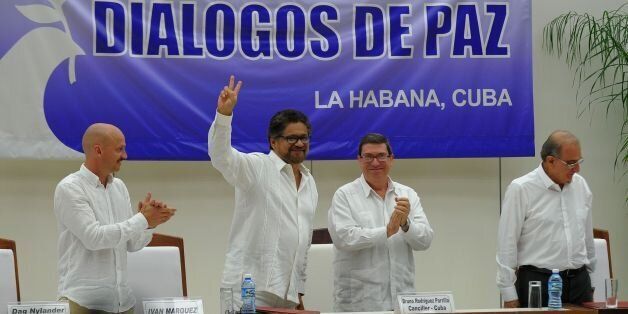 FARC-EP Commander Ivan Marquez flashes the V sign after the signing of the agreement at the conclusion of the peace talks at the Convention Palace in Havana, on August 24, 2016, next to Norway's guarantor for the peace talks, Dag Nylander (L), Cuban Foreign Minister Bruno Rodriguez and Colombian government head of delegation Humberto de la Calle (R).Colombia's government and FARC rebels announced Wednesday that they have reached a historic peace accord to end their half-century civil war, the last major armed conflict in the Americas. / AFP / YAMIL LAGE (Photo credit should read YAMIL LAGE/AFP/Getty Images)