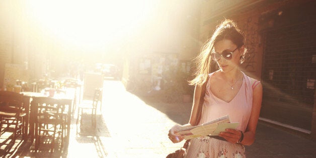 young brunette sightseeing on the street, looking at the map, lit by the magic hour sunlight.