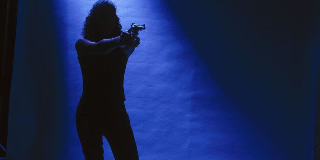 Woman in the spotlight and pointing a gun