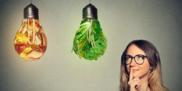 Portrait beautiful woman in glasses thinking looking up at junk food and green vegetables shaped as light bulb isolated on gray background. Diet choice right nutrition healthy lifestyle concept