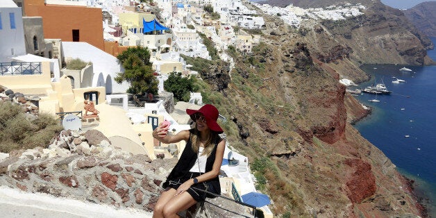 A tourist takes a selfie in the village of Oia on the Greek island of Santorini, Greece, July 1, 2015. REUTERS/Cathal McNaughton/Files