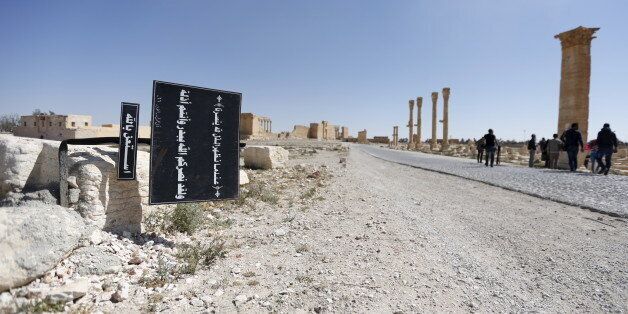 A billboard (L) with Koranic verses is seen in the historic city of Palmyra, in Homs Governorate, Syria April 1, 2016. REUTERS/Omar Sanadiki SEARCH
