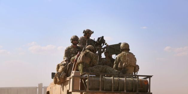 Armed men in uniform identified by Syrian Democratic forces as US special operations forces ride in the back of a pickup truck in the village of Fatisah in the northern Syrian province of Raqa on May 25, 2016. US-backed Syrian fighters and Iraqi forces pressed twin assaults against the Islamic State group, in two of the most important ground offensives yet against the jihadists. The Syrian Democratic Forces (SDF), formed in October 2015, announced on May 24 its push for IS territory north of Raqa city, which is around 90 kilometres (55 miles) south of the Syrian-Turkish border and home to an estimated 300,000 people. The SDF is dominated by the Kurdish People's Protection Units (YPG) -- largely considered the most effective independent anti-IS force on the ground in Syria -- but it also includes Arab Muslim and Christian fighters. / AFP / DELIL SOULEIMAN (Photo credit should read DELIL SOULEIMAN/AFP/Getty Images)