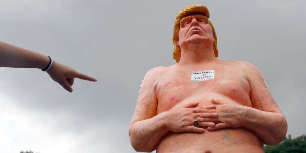 A woman points at a statue of a naked Republican presidential candidate Donald Trump, Thursday, Aug. 18, 2016 in New York's Union Square. The statue was removed by New York City Department of Parks & Recreation employees. (AP Photo/Mary Altaffer)
