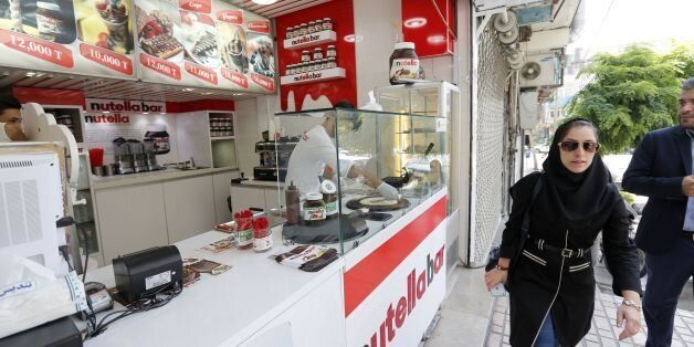 An Iranian worker prepares a crepe at Nutella Bar, a popular chain selling waffles and crepes in Tehran on August 17, 2016.The state-run Academy of Persian Language and Literature has imposed a number of changes in recent years, particularly aimed at curbing the intrusion of English. The Academy's latest target has caused some bafflement: a popular chain of waffle and crepe cafes called Nutella Bars after the Italian hazelnut and cocoa spread in which they smother their snacks. / AFP / ATTA KENARE / TO GO WITH AFP STORY BY ERIC RANDOLPH AND ALI NOORANI (Photo credit should read ATTA KENARE/AFP/Getty Images)