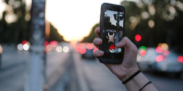 PARIS, FRANCE - AUGUST 17: A woman launches a Pokeball to catch a Scarabrute (Pinsir) character while playing Nintendo Co.'s Pokemon Go augmented-reality game, while crossing the road, on the Avenue des Champs Elysees, near Place de la Concorde on August 17, 2016 in Paris, France. (Photo by Edward Berthelot/Getty Images)