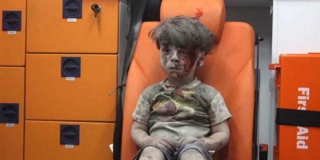 ALEPPO, SYRIA - AUGUST 17: (EDITORS NOTE: Image contains graphic content.) 5-year-old wounded Syrian kid Omran Daqneesh sits alone in the back of the ambulance after he got injured during Russian or Assad regime forces air strike targeting the Qaterji neighbourhood of Aleppo on August 17, 2016. (Photo by Mahmud Rslan/Anadolu Agency/Getty Images)