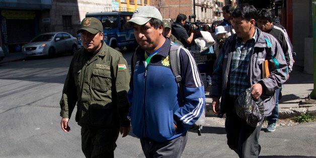 Police officer escort independent miners detained for questioning in the death of Bolivia's late Deputy Minister of Internal Affairs Rodolfo Illanes, in La Paz, Bolivia Friday, Aug. 26, 2016. Striking Bolivian miners kidnapped and beat to death Illanes Thursday, in a shocking spasm of violence following weeks of tension over dwindling paychecks in a region hit hard by falling metal prices. The miners were demanding they be allowed to work for private companies, who promise to put more cash in their pockets. (AP Photo/Juan Karita)
