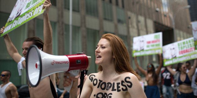 Rachel Jessee speaks into a megaphone while riding atop a car during the GoTopless Day Parade, Sunday, Aug. 23, 2015, in New York. The parade took to the streets to counter critics who are complaining about topless tip-seekers in Times Square. Appearing bare-breasted is legal in New York. But Mayor Bill de Blasio and police Commissioner Bill Bratton say the body-painted women in the square who take photos with tourists are a nuisance. (AP Photo/Kevin Hagen)
