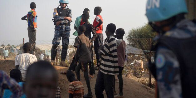 In this photo taken Tuesday, Jan. 19, 2016, a United Nations peacekeeper stands with displaced children on a wall around the United Nations base in the capital Juba, South Sudan. When a delegation of South Sudanese rebels returned to the government-controlled capital Juba last month after two years of war, many refugees thought they would finally return to the homes they fled. But prospects for peace seem dim after the government and rebels missed a deadline last week to form a power-sharing go
