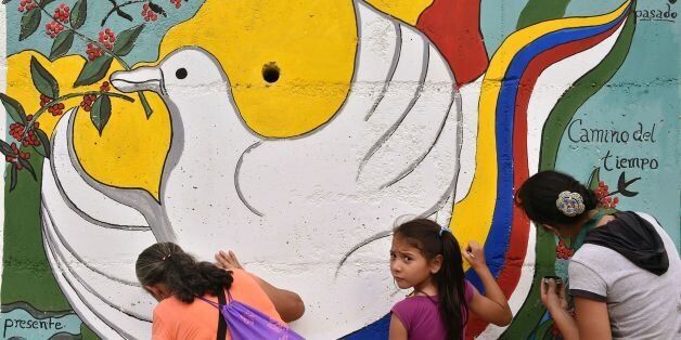 Women and a girl paint a mural alluding to peace on the road leading to Planadas, Tolima department, Colombia on August 26, 2016, where a peasant uprising in 1964 led to the birth of the Revolutionary Armed Forces of Colombia (FARC).The historic ceasefire between Colombia's government and the FARC rebel group will not end the government's commitment to fighting crime, the country's defense minister said Friday. / AFP / GUILLERMO LEGARIA (Photo credit should read GUILLERMO LEGARIA/AFP/Getty Images)