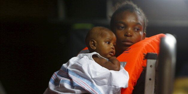 A migrant carries her baby on the Migrant Offshore Aid Station (MOAS) ship MV Phoenix while waiting to be transferred to the Norwegian ship Siem Pilot off the coast of Libya August 6, 2015. An estimated 700 migrants on an overloaded wooden boat were rescued 10.5 miles (16 kilometres) off the coast of Libya by the international non-governmental organisations Medecins san Frontiere (MSF) and MOAS without loss of life on Thursday afternoon, according to MSF and MOAS, a day after more than 200 migrants are feared to have drowned in the latest Mediterranean boat tragedy after rescuers saved over 370 people from a capsized boat thought to be carrying 600.REUTERS/Darrin Zammit Lupi MALTA OUT. NO COMMERCIAL OR EDITORIAL SALES IN MALTA