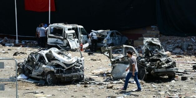 Turkish rescue workers stand by the wreckage of a vehicle as a Turkish police officer inspects a destroyed car and a man walks among the remains at the blast scene following a car bomb attack on a police station in the eastern Turkish city of Elazig, on August 18, 2016.At least three people were killed and another 120 injured on August 18, 2016 in a car bomb attack on a police headquarters in eastern Turkey, a local security source said. The explosion, blamed by Defence Minister Fikri Isik on the outlawed Kurdistan Workers' Party (PKK), happened in the garden of the four-storey building in Elazig. / AFP / ILYAS AKENGIN (Photo credit should read ILYAS AKENGIN/AFP/Getty Images)