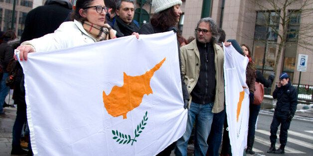 People hold a banner with the flag of Cyprus on it during a demonstration outside of an emergency eurogroup meeting in Brussels on Sunday, March 24, 2013. The EU says a top official will chair a high-level meeting on Cyprus in a last-ditch effort to seal a deal before finance ministers decide whether the island nation gets a 10 billion euro bailout loan to save it from bankruptcy. (AP Photo/Virginia Mayo)