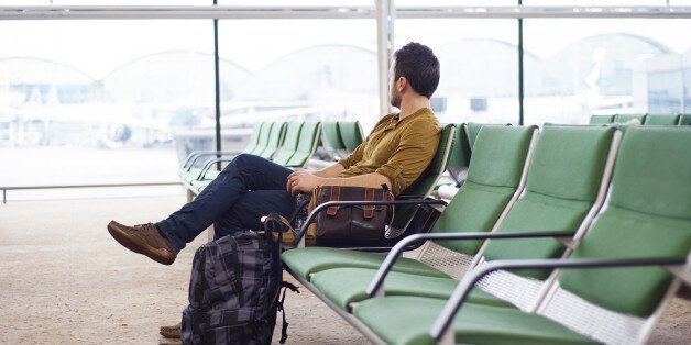 Young man is waiting at the airport for his flight .