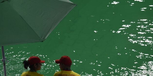 A picture taken on August 10, 2016 at the Maria Lenk Aquatics Stadium in Rio de Janeiro shows people standing near the diving pool of the Rio 2016 Olympic Games. Red-faced Rio Olympics organisers anxiously waited for the diving water to turn back from a nervy green to classic blue as a lack of chemicals was revealed as the cause of the colour changes. Heavy rain slowed the flow of new chemicals added to the water which was also green in the pool used for the synchronised swimming and water-polo. / AFP / GABRIEL BOUYS (Photo credit should read GABRIEL BOUYS/AFP/Getty Images)