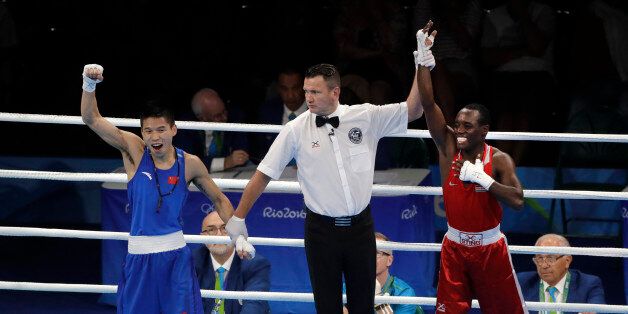 The referee looks at China's Bin LV, left, as he lifts the hand of Kenya's Peter Mungai Warui after a men's light flyweight 49-kg preliminary boxing match at the 2016 Summer Olympics in Rio de Janeiro, Brazil, Monday, Aug. 8, 2016. (AP Photo/Jae C. Hong)