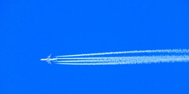 Airplane with chemtrails on blue sky