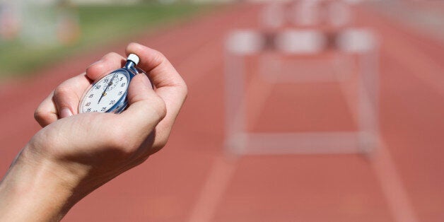 Hand with a stopwatch by hurdles