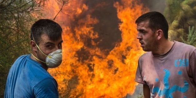 Villagers fight a forest fire in Arbo, in the Pontevedra region northwestern Spain, on August 11, 2016. / AFP / MIGUEL RIOPA (Photo credit should read MIGUEL RIOPA/AFP/Getty Images)