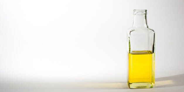 Half full bottle of olive oil on white background.
