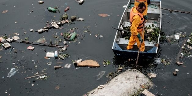 Environment Institute of Rio de Janeiro State (INEA) staffers collect a bed mattress as the tide moves away from the 'eco-barrier' set up to catch floating debris before they enter Guanabara Bay at the mouth of the Meriti river, in Duque de Caxias, next to Rio de Janeiro, Brazil, on July 20, 2016. / AFP / YASUYOSHI CHIBA (Photo credit should read YASUYOSHI CHIBA/AFP/Getty Images)