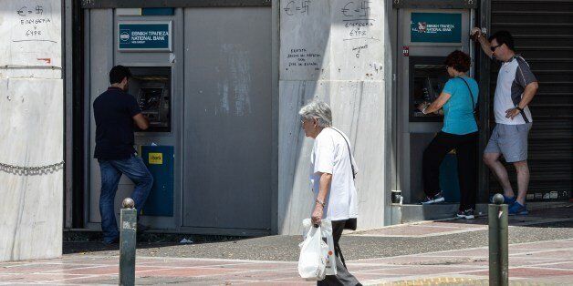 People withdraw money from ATMs in downtown Athens on July 5, 2015. Greek voters headed to the polls to vote in a historic, tightly fought referendum on whether to accept worsening austerity in exchange for more bailout funds, in a gamble that could see it crash out of the euro. AFP PHOTO / ANDREAS SOLARO (Photo credit should read ANDREAS SOLARO/AFP/Getty Images)
