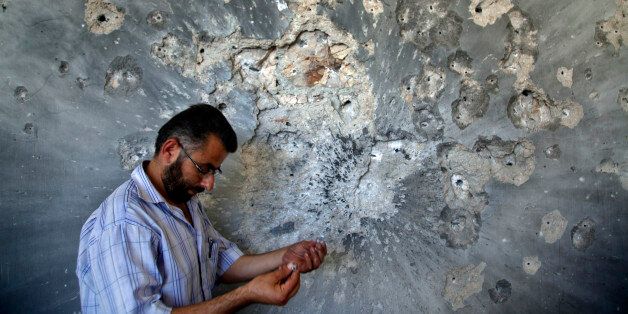 FILE - In this Aug. 5, 2012 file photo, a Syrian man holds bullets he picked from the wall of a damaged house in the town of Atareb, on the outskirts of Aleppo, Syria, Sunday, Aug. 5, 2012. Syrian opposition activists said Sunday, July 17, 2016 that government forces and their allies have closed the only road leading into and out of rebel-held parts of the northern city of Aleppo, besieging hundreds of thousands of people. The Britain-based Syrian Observatory for Human Rights says government forces and members of Lebanonâs Hezbollah group reached the Castello road Sunday, closing it and raising fears of a humanitarian crisis. (AP Photo/Khalil Hamra, File)