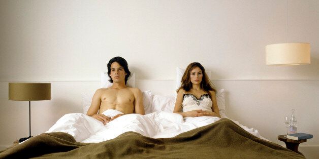 serious looking couple lying together in bed