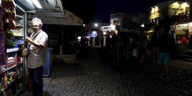 A man buys snacks in the village of Fira on the Greek island of Santorini, Greece, July 1, 2015. Greece's last-minute overtures to international creditors for financial aid on Tuesday were not enough to save the country from becoming the first developed economy to default on a loan with the International Monetary Fund. REUTERS/Cathal McNaughton